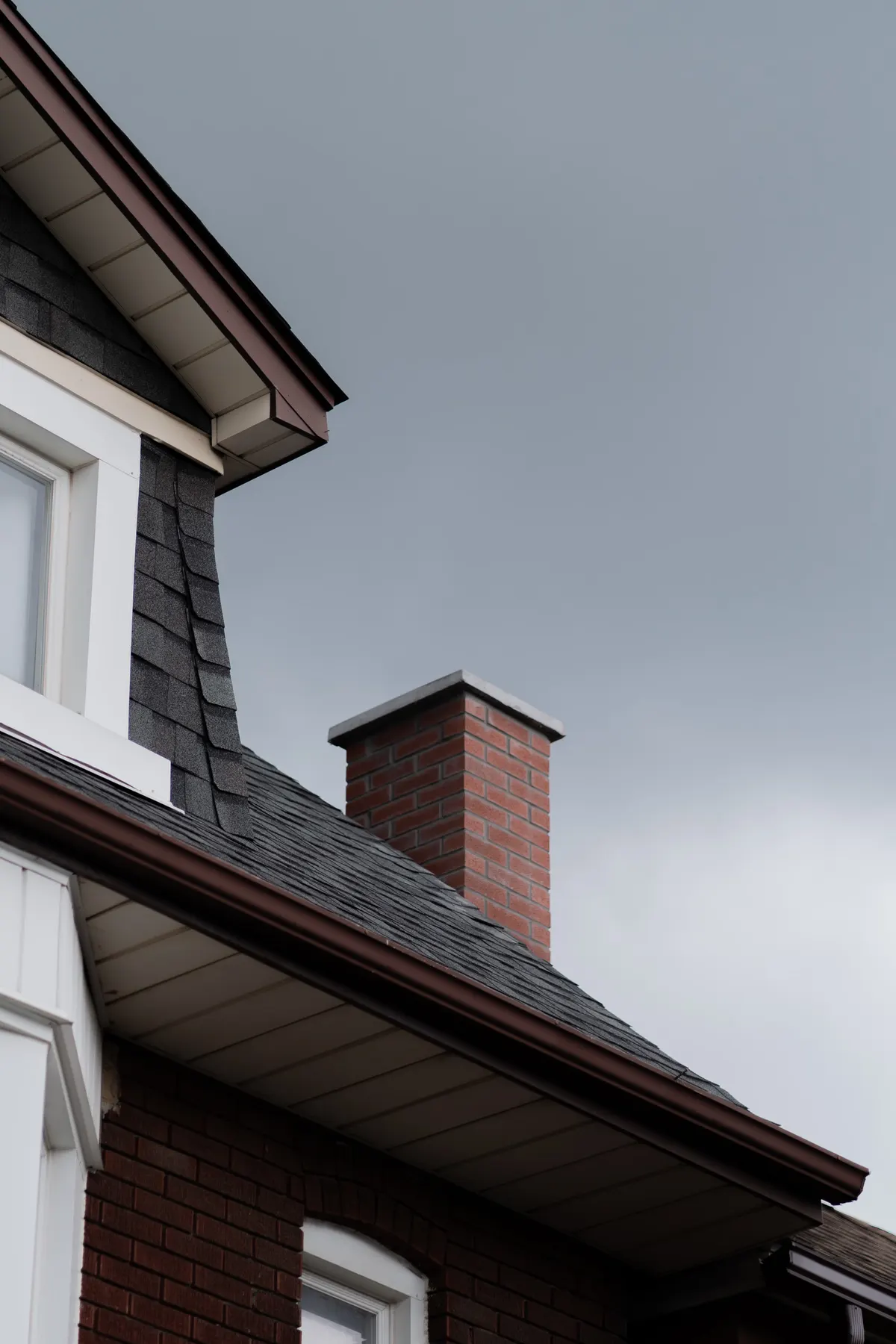 Close-up of a shingle roof with brick chimney