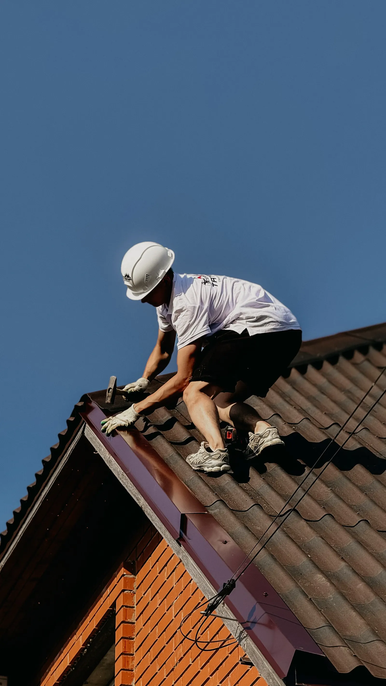 Roofer in safety helmet repairing a roof
