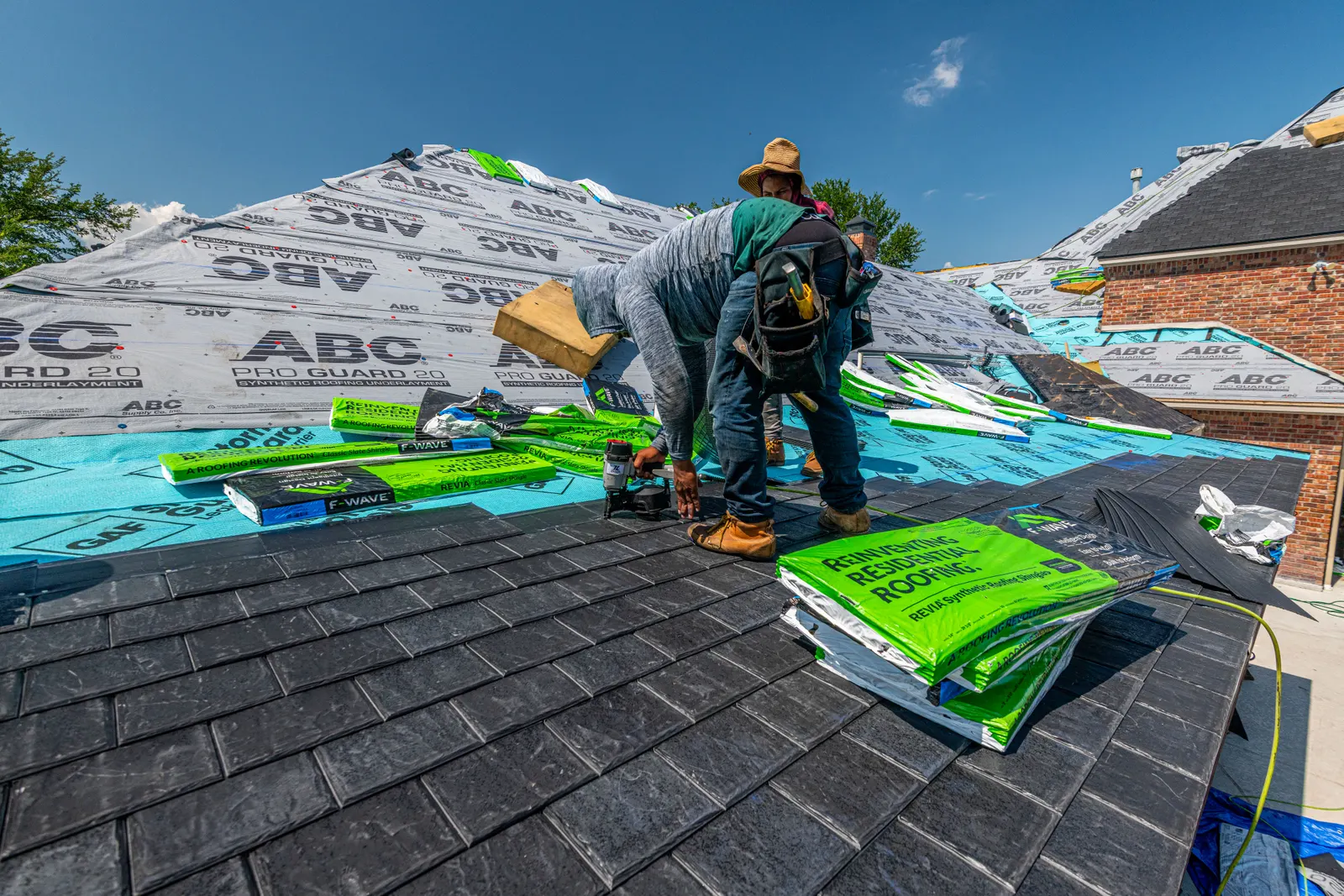Crew installing a synthetic slate roof on a brick home