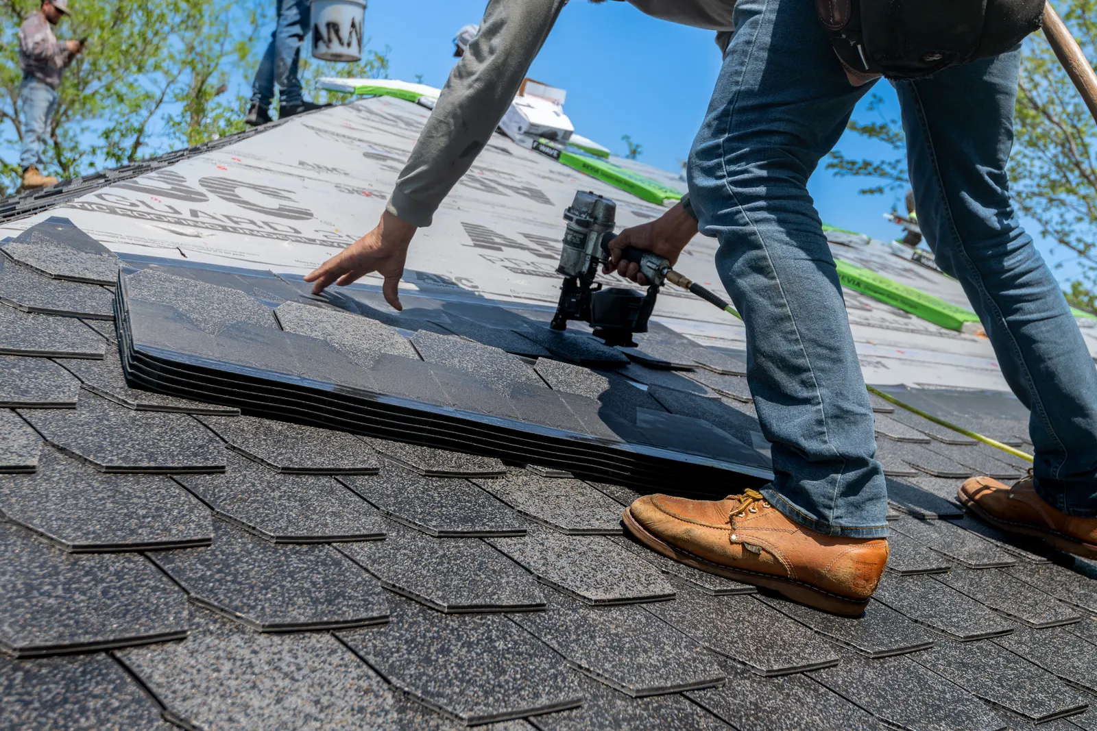 Roofer installing architectural shingles on a new steep-slope roof